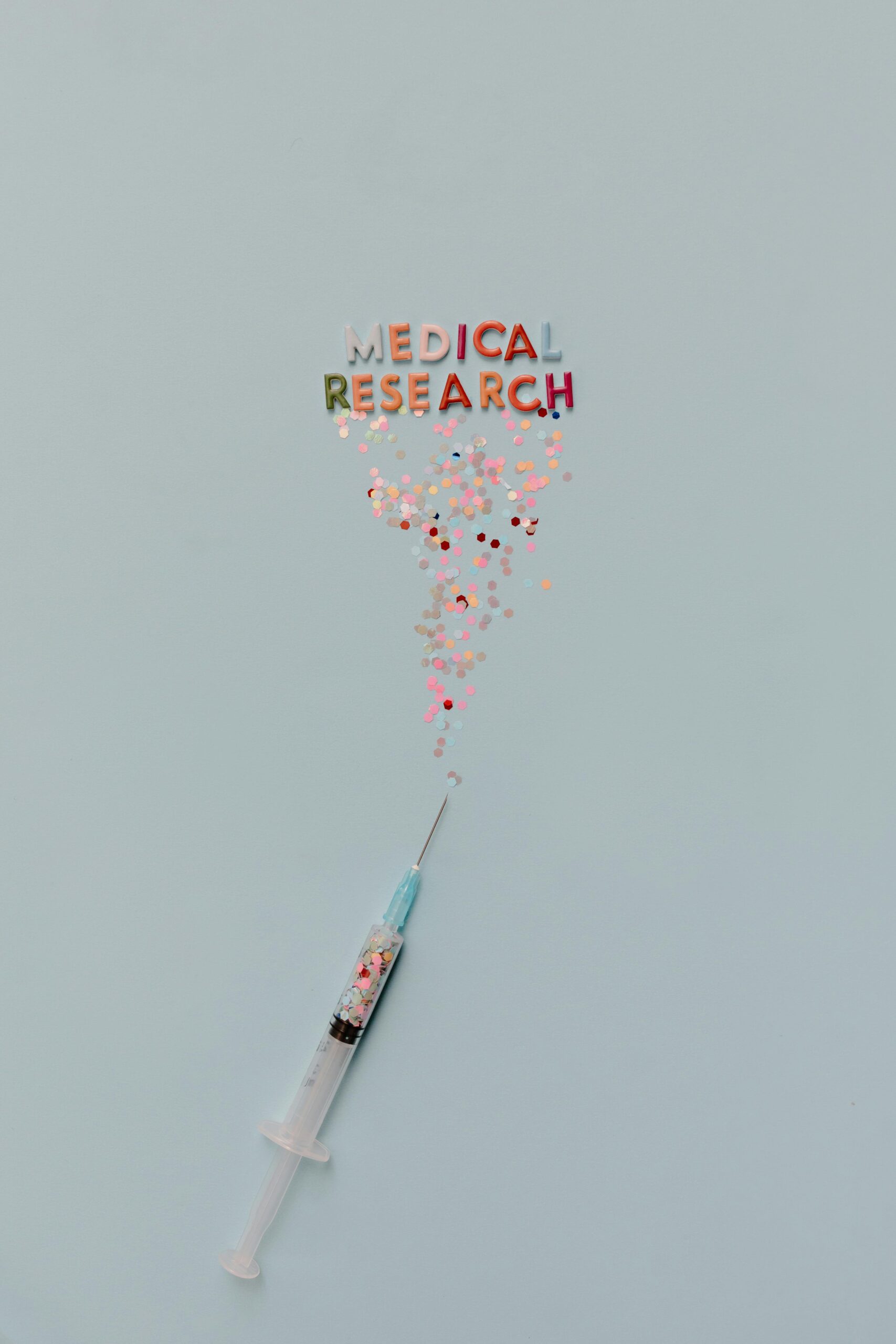 Syringe releasing confetti with 'MEDICAL RESEARCH' text on a blue background.